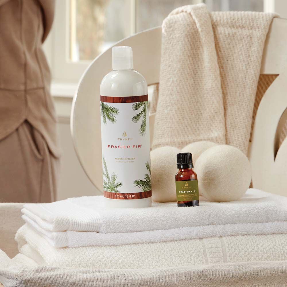 Thymes Frasier Fir Fabric Softener laundry care on top of folded linens next to Frasier Fir Wool Dryer Balls and Fragrance Oil image number 2
